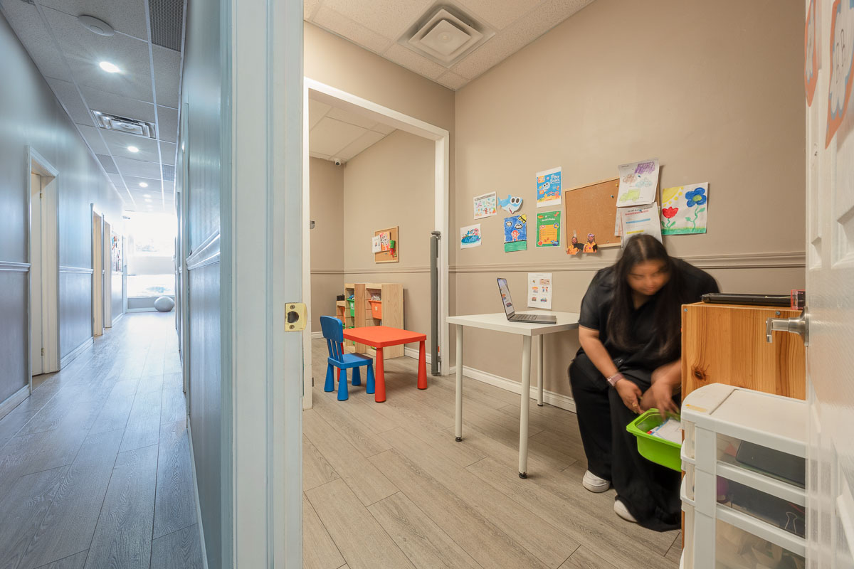 AlphaBee therapist setting out materials before a session in a therapy room at the Scarborough centre, with a child-sized table and chairs and artwork on the walls