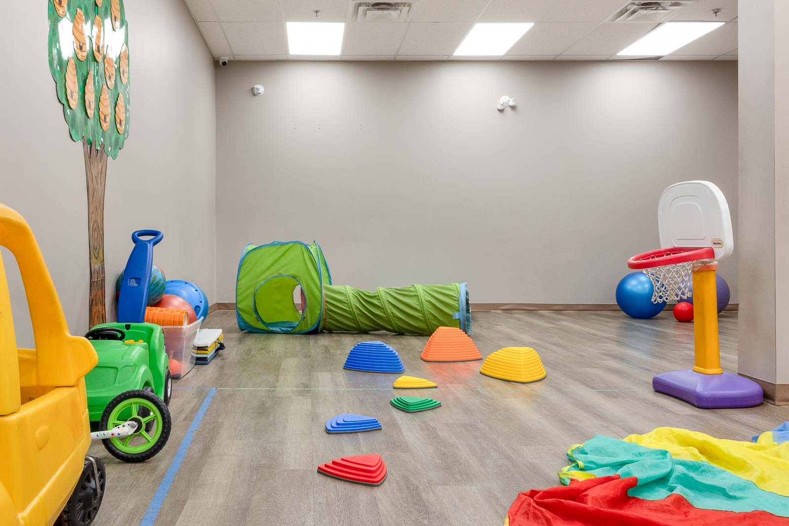 Tunnel, stepping stones and a basketball hoop in the play room at AlphaBee Etobicoke
